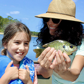 Woman holding fish alongside child 